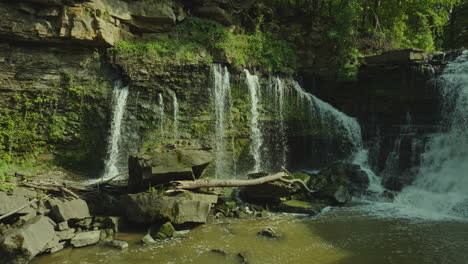drone semi orbit capturing upper balls falls in ontario, with lush green forest and layered rocks