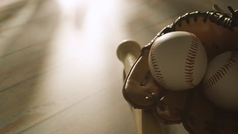 achtergrondverlichting close-up studio baseball stilleven met bat bal en catcher handschoen op bejaarde houten vloer