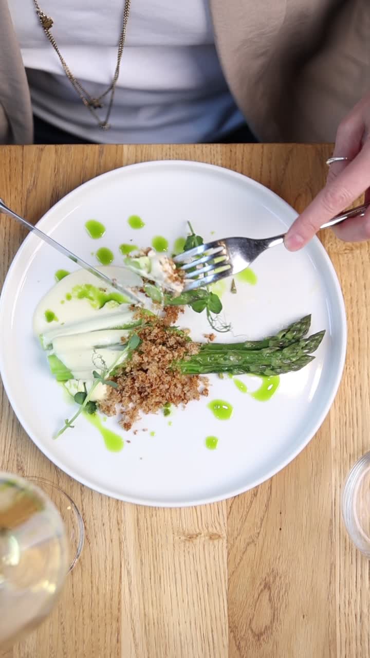 Pohled shora na osobu, která jí gurmánský chřestový pokrm v restauraci