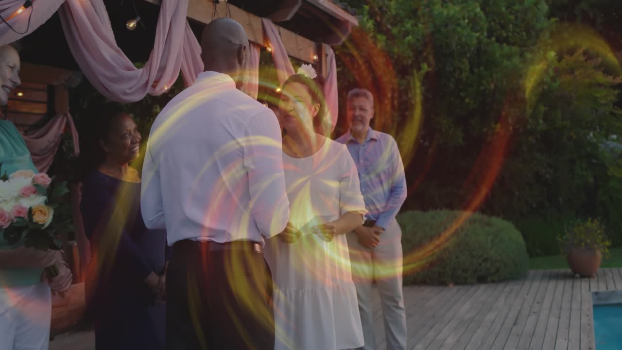 Couple exchanging wedding vows while reading cards on deck, swirl briefly hiding pergola and couple