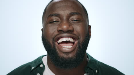 Portrait-of-emotional-african-american-man-smiling-on-light-background.