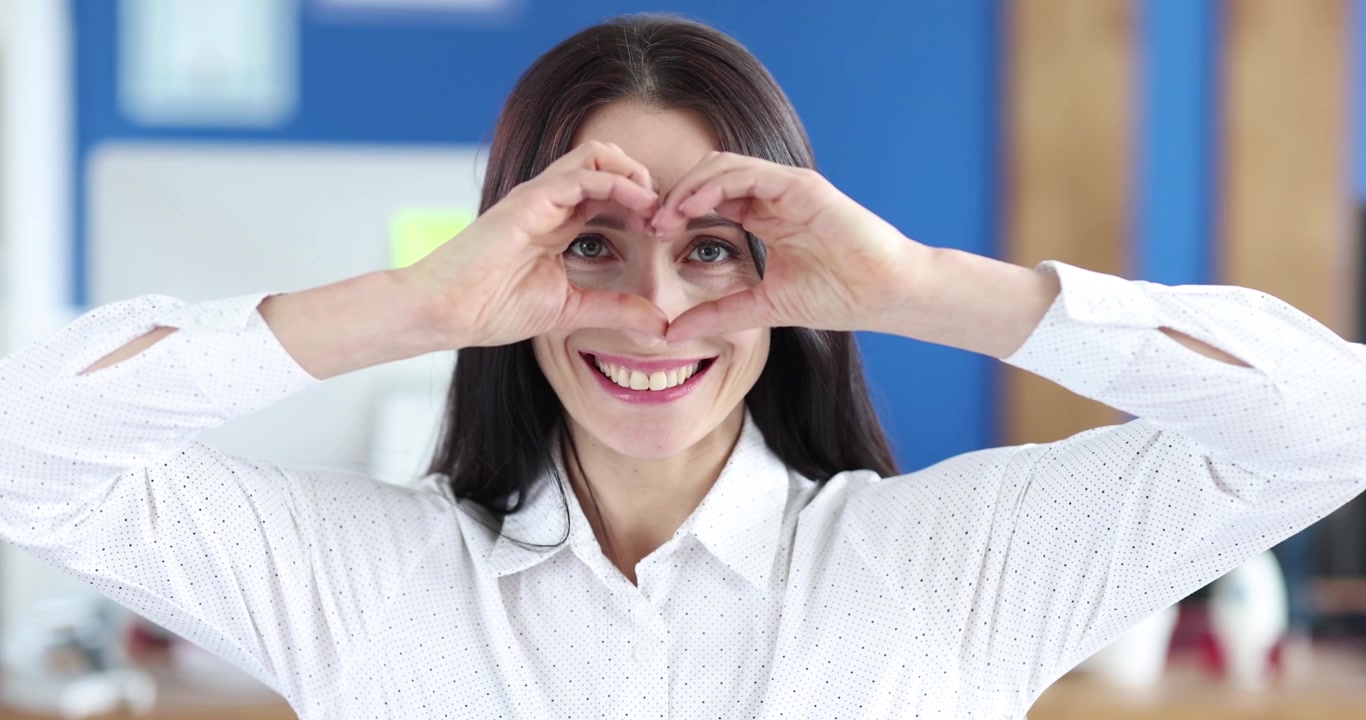 Mujer sonriente haciendo gesto de corazón, película 4k en cámara lenta