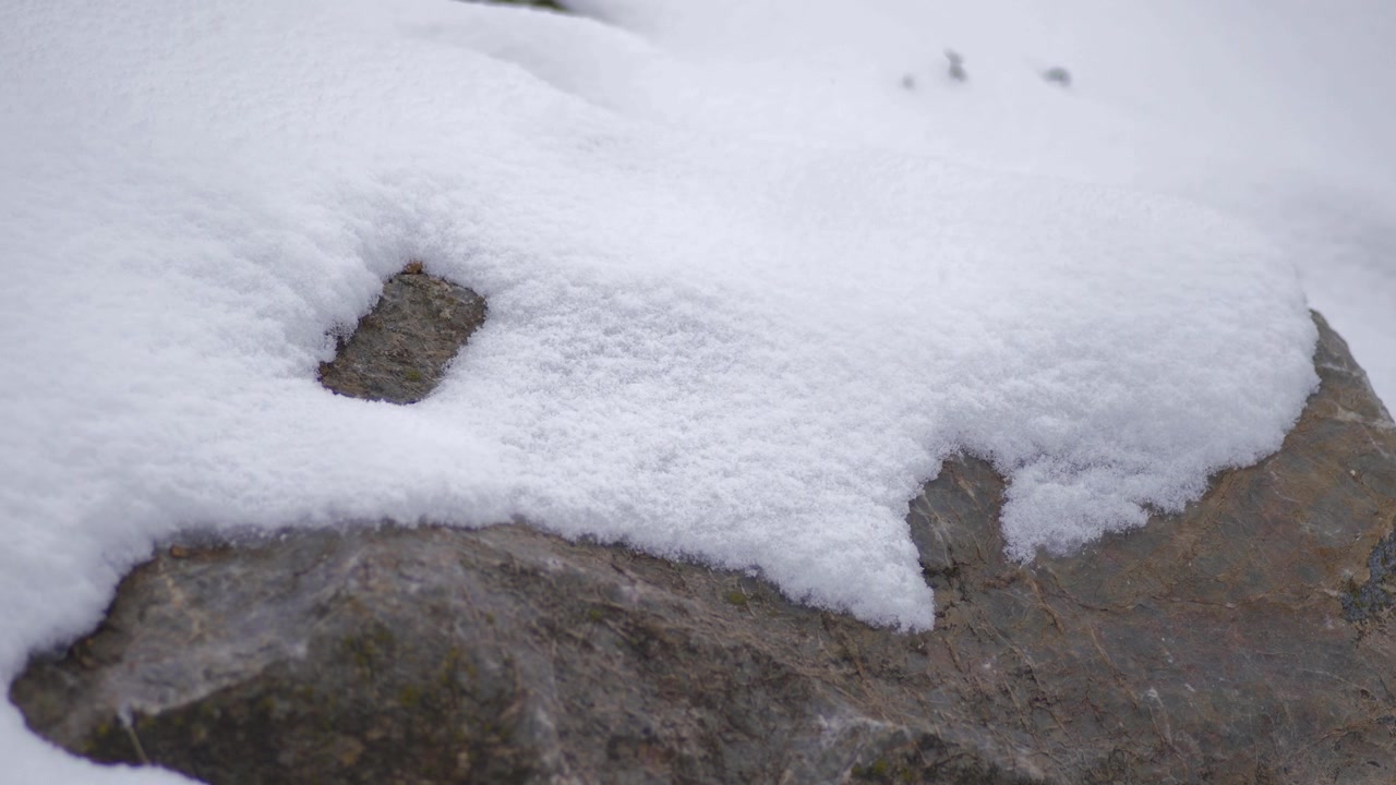 Leichter Schneefall auf einem großen Felsen im Winter