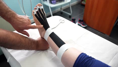 pies con cinta de kinesiología durante una sesión de terapia para aliviar el dolor