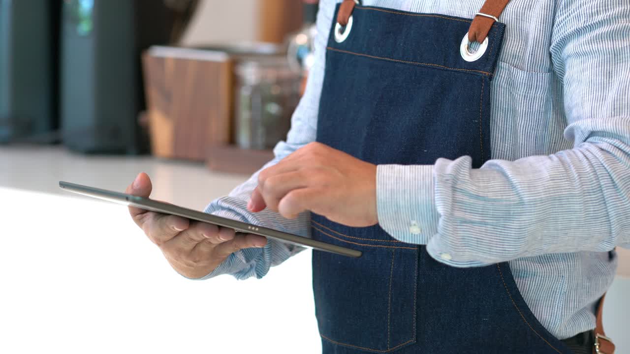 4K Asian male coffee shop owner using digital tablet briefing staff before working.