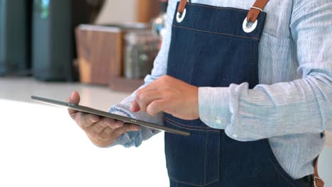 4k asian male coffee shop owner using digital tablet briefing staff before working.