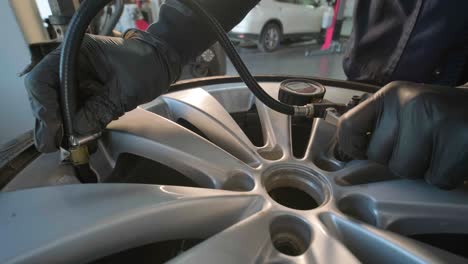 filling the wheel with air from the compressor at the service station. service station, close-up man checking tire pressure, car repair and tyre inflation. professional tire fitting at car service