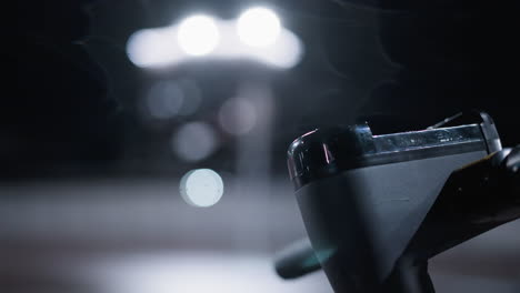 close view of a parked electric scooter bike handle with soft bokeh light effects in the background and a blurred view of cars passing by