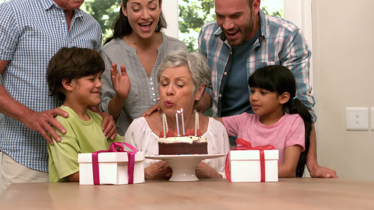Cute grandmother blowing her candles with her family
