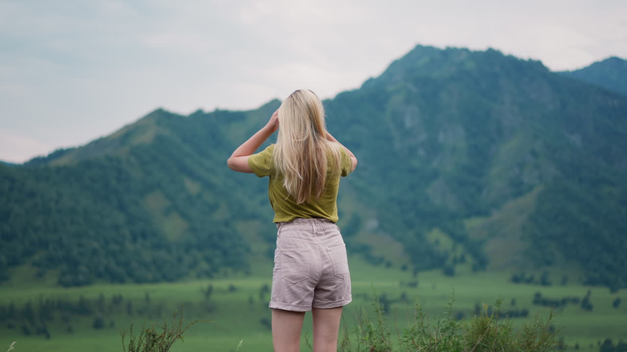 Female tourist adjusts shorts and shakes hair at eco reserve
