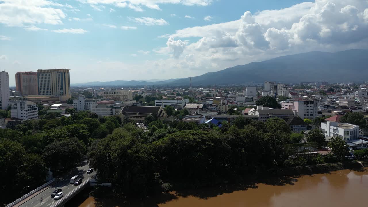 tiro aéreo de levantamiento lento sobre el río ping con la ciudad de chiang mai en la distancia