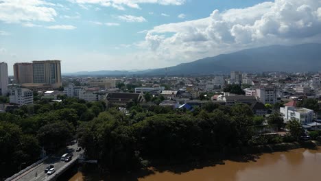 Tiro-Aéreo-De-Levantamiento-Lento-Sobre-El-Río-Ping-Con-La-Ciudad-De-Chiang-Mai-En-La-Distancia