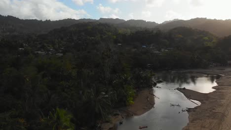 the sun rays shine brilliantly on the river at it flows into the ocean with sexy girl sitting at the river edge at grande riviere beach, trinidad