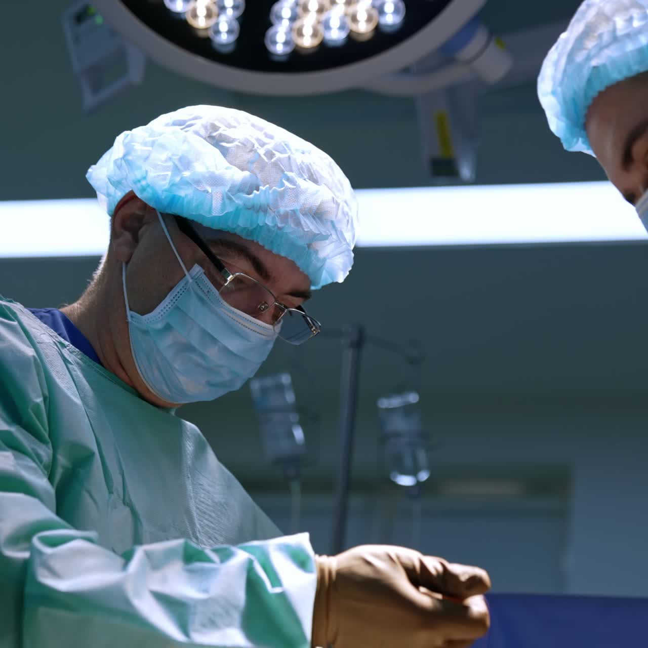 Professional surgeons wearing uniform and protective masks work at operation. Low angle view