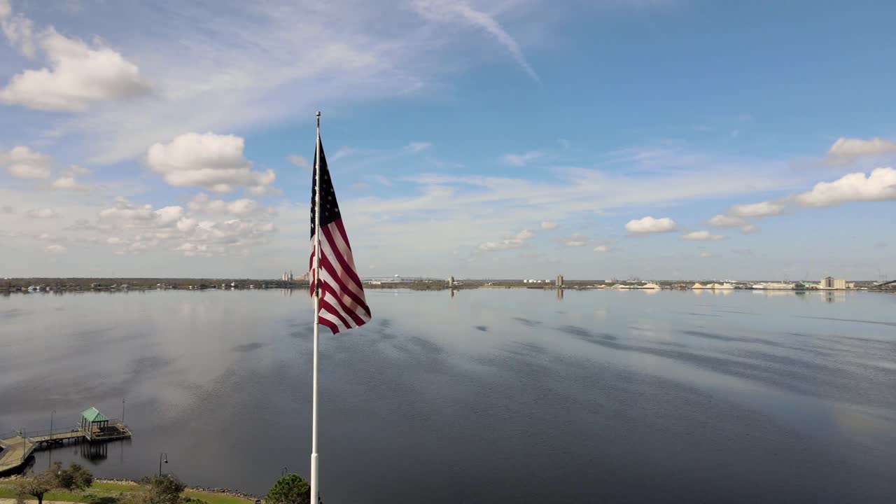 imágenes aéreas de drones de una bandera estadounidense roja, blanca y azul ondeando y aleteando en el viento en un mástil de bandera alto en iowa