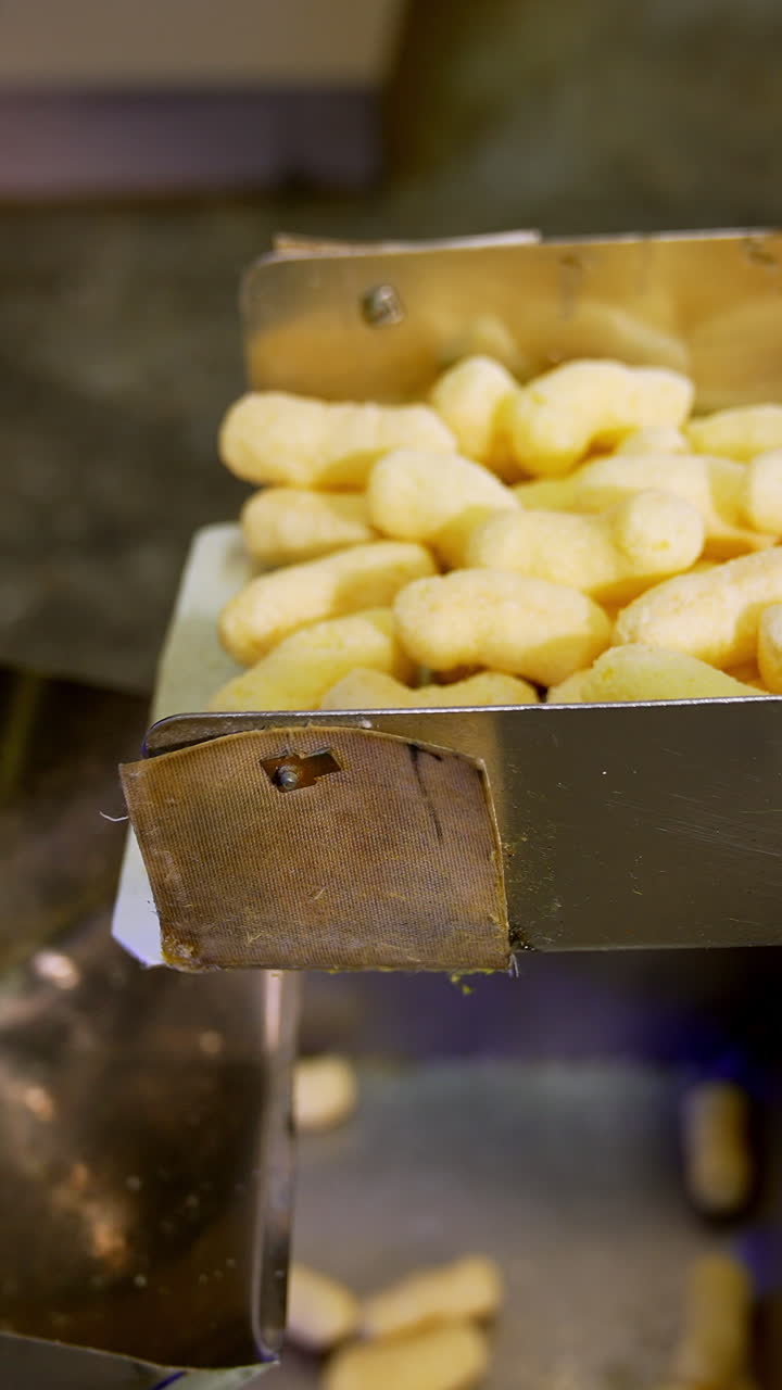 Factory producing crispy corn sticks. Sweet healthy puffcorn sticks making. Vertical video