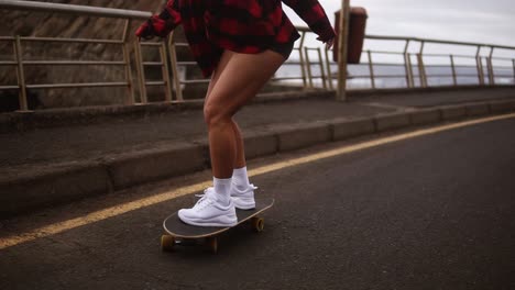 Young-Pretty-Beautiful-Brunette-Hipster-Woman-In-Plaid-Coat-Having-Fun-Riding-Skateboard-Longboard-Downhill-On-Beautiful-Road-In-Slow-Motion