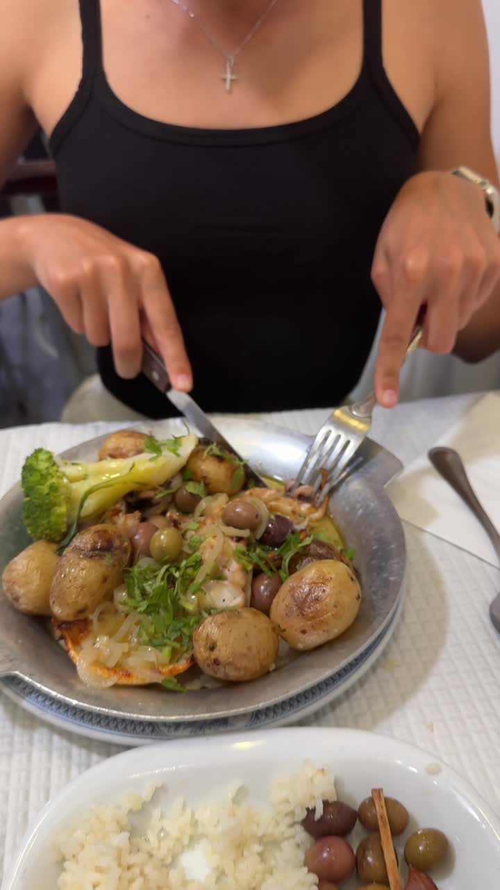 Person eating a seafood dish with potatoes and olives