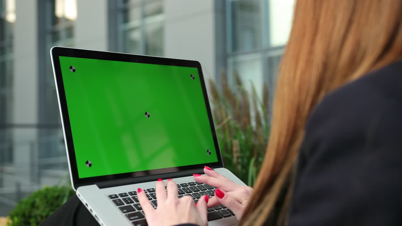 las manos de las mujeres trabajando en la pantalla verde de la computadora portátil. la mujer usando la llave de croma del portátil
