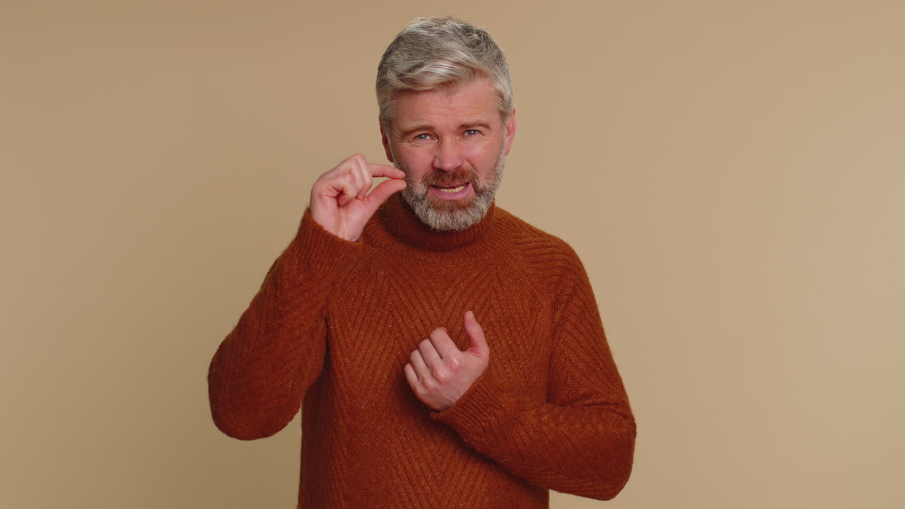 Man in brown sweater smiling and pointing