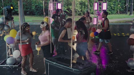 diverse group of people dancing and celebrating at an outdoor party with balloons and confetti