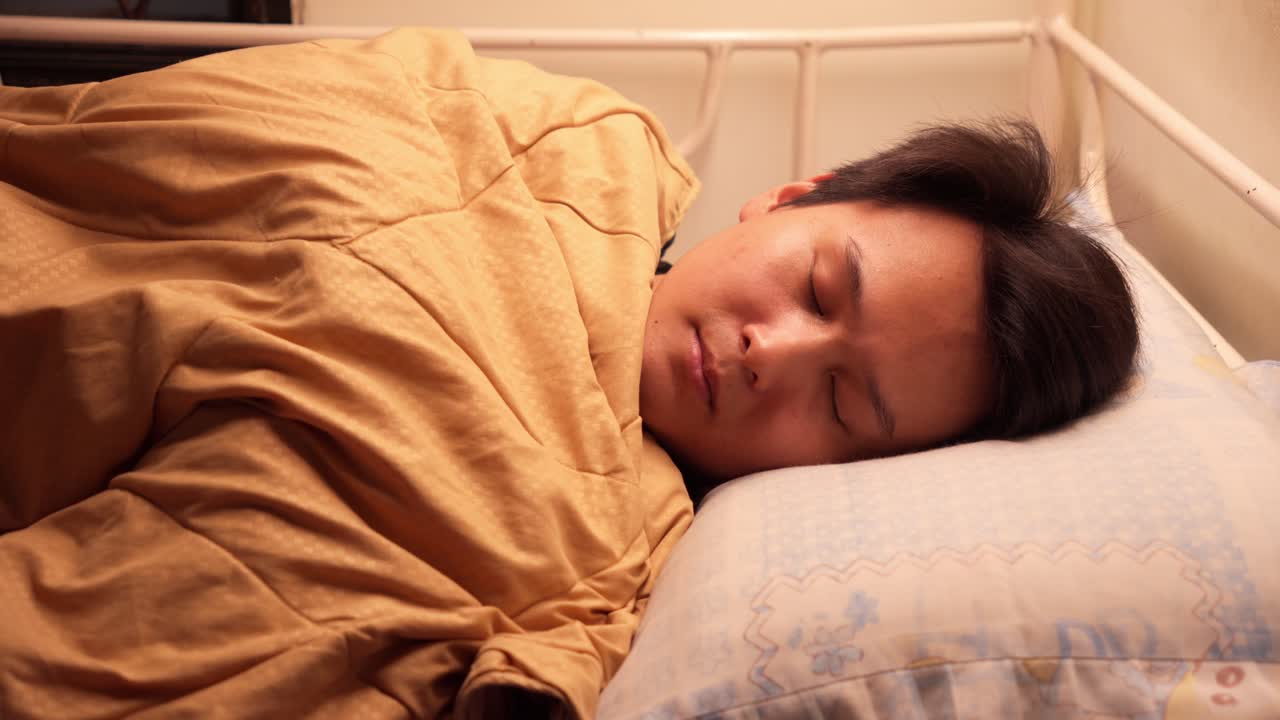 Chinese man going to sleep in a little bed. Close up