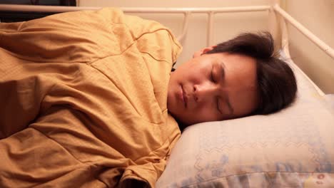 chinese man going to sleep in a little bed. close up