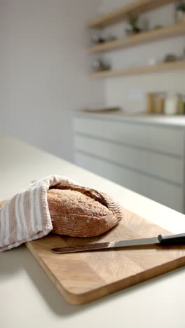 vertical video: freshly baked bread on cutting board with knife in modern kitchen