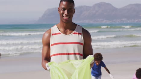 retrato de un padre afroamericano con sus hijos recolectando basura y botellas de la playa