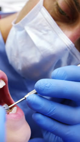 dentist examining a young patient with tools