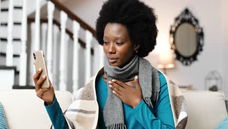 close up of african american woman sitting at home and talking on video on cellphone