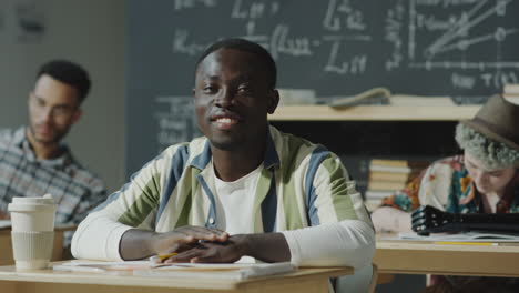young male student smiling in a classroom