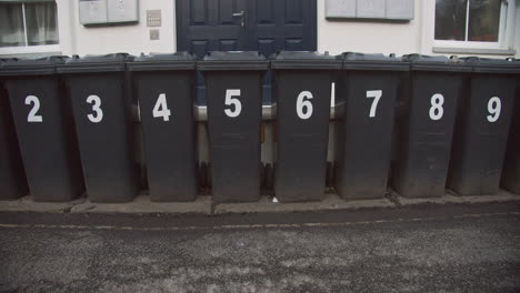 numbered rubbish bins lined up outside apartment complex, slow pan