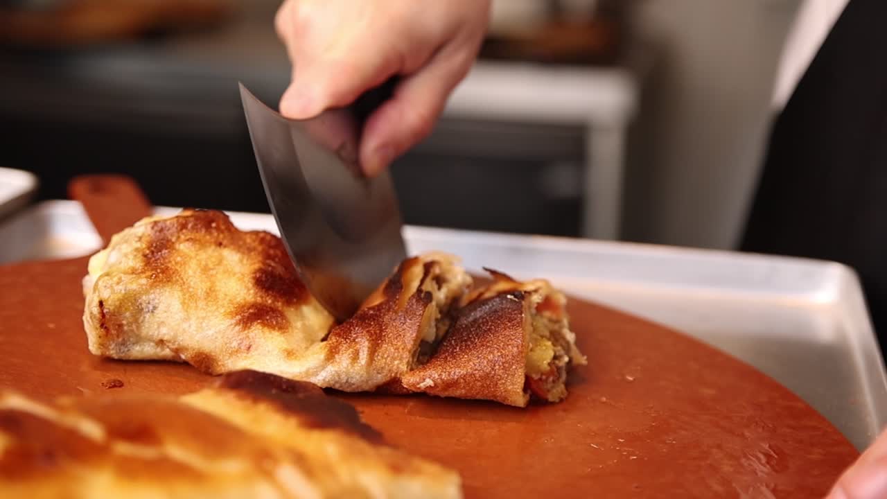 Primo piano di una mano che taglia un prodotto da forno dorato