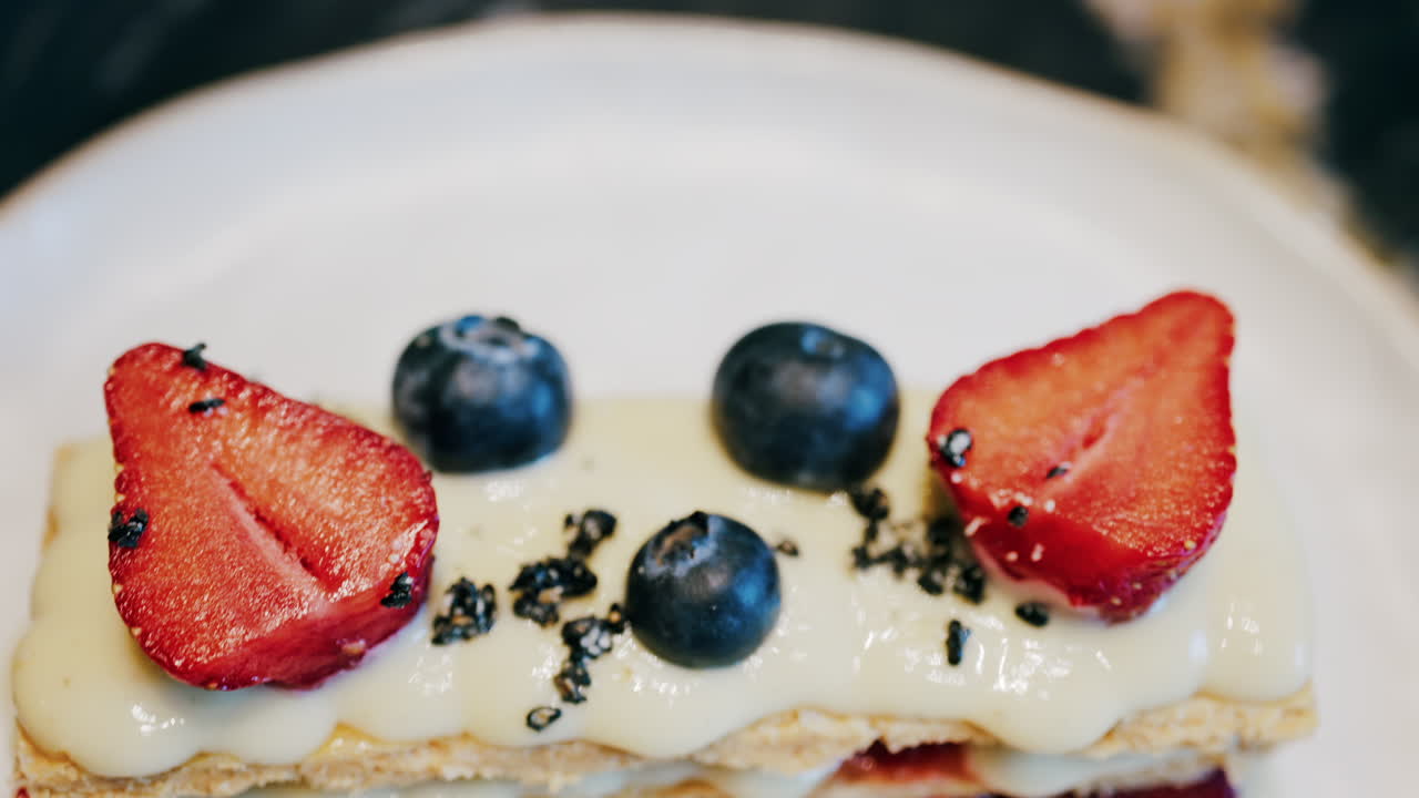 Close up of a Napoleon cake with strawberries and blueberries on a white plate at a cafe
