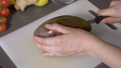cutting fresh mango fruit on the chopping board with a knife - closeup shot