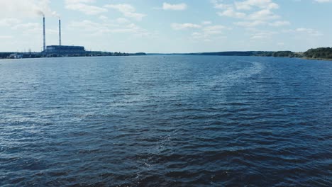 quick motion camera over the blue river. natural water background. industrial factory near the river. beautiful lake under the blue sky.
