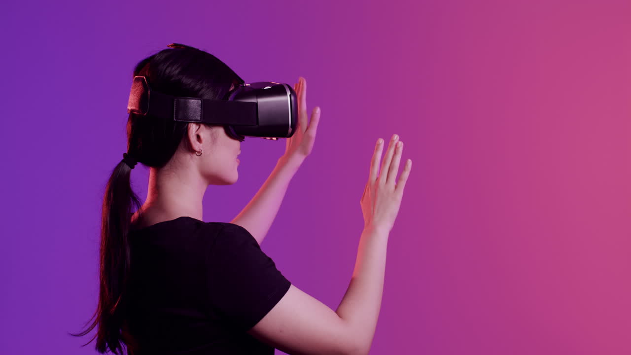 Asian woman using vr headset, touching screen on purple background, copy space, slow motion