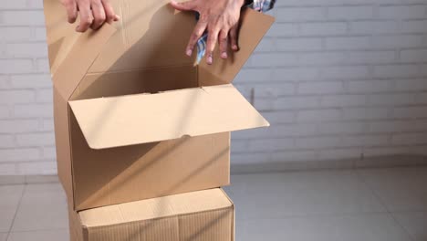 person, die eine kartonbox öffnet