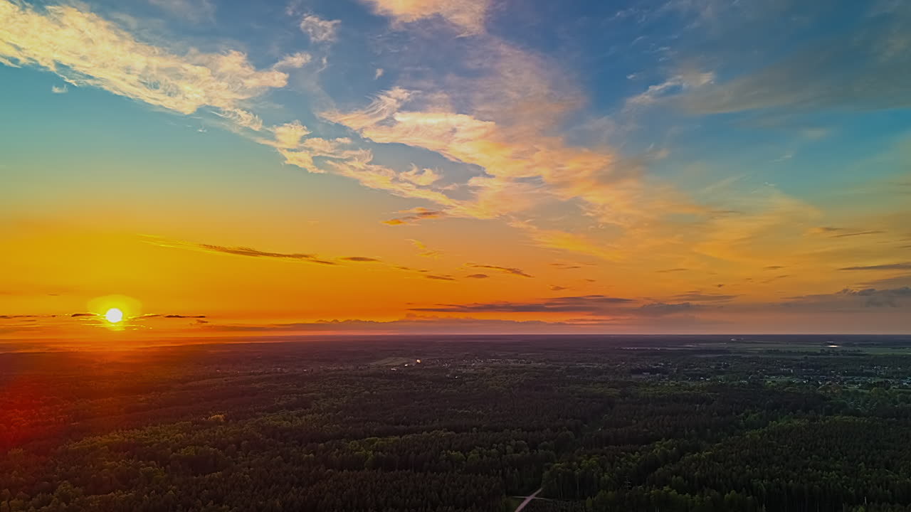 Sunset hyperlapse over dense forest landscape with vibrant orange and blue sky