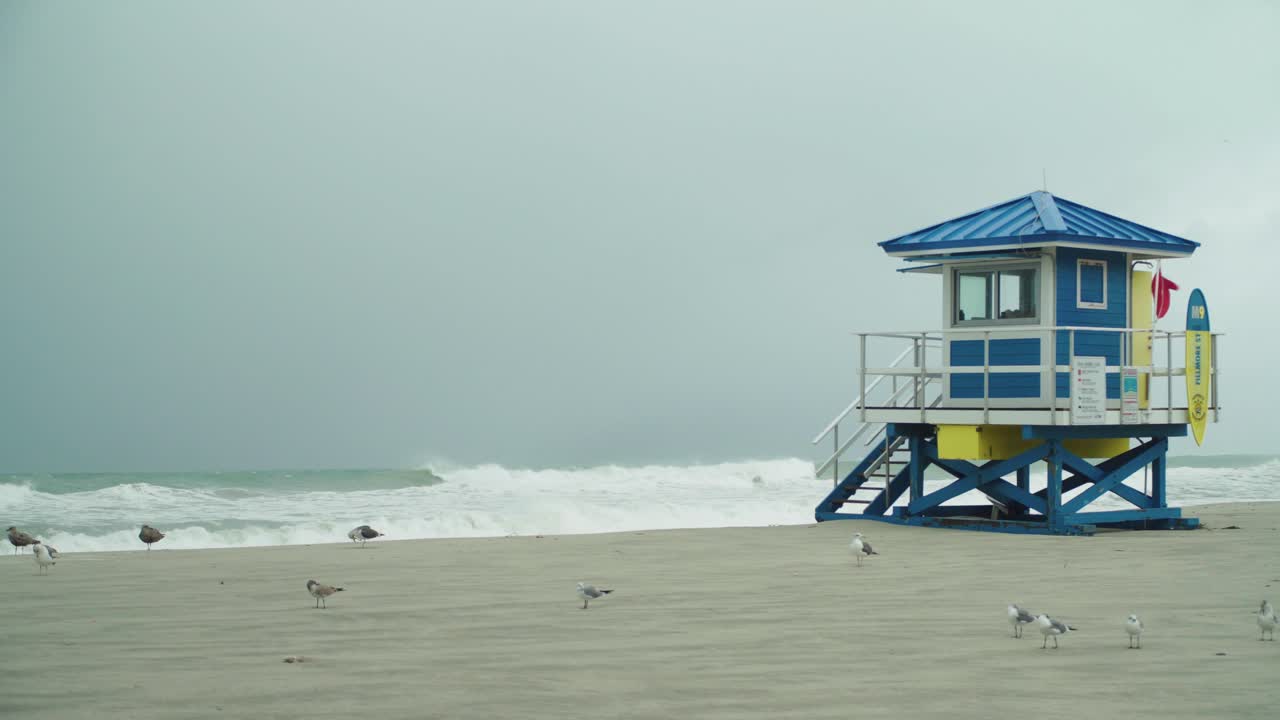 tormenta tropical, casa de salvavidas con bandera roja en la playa vacía