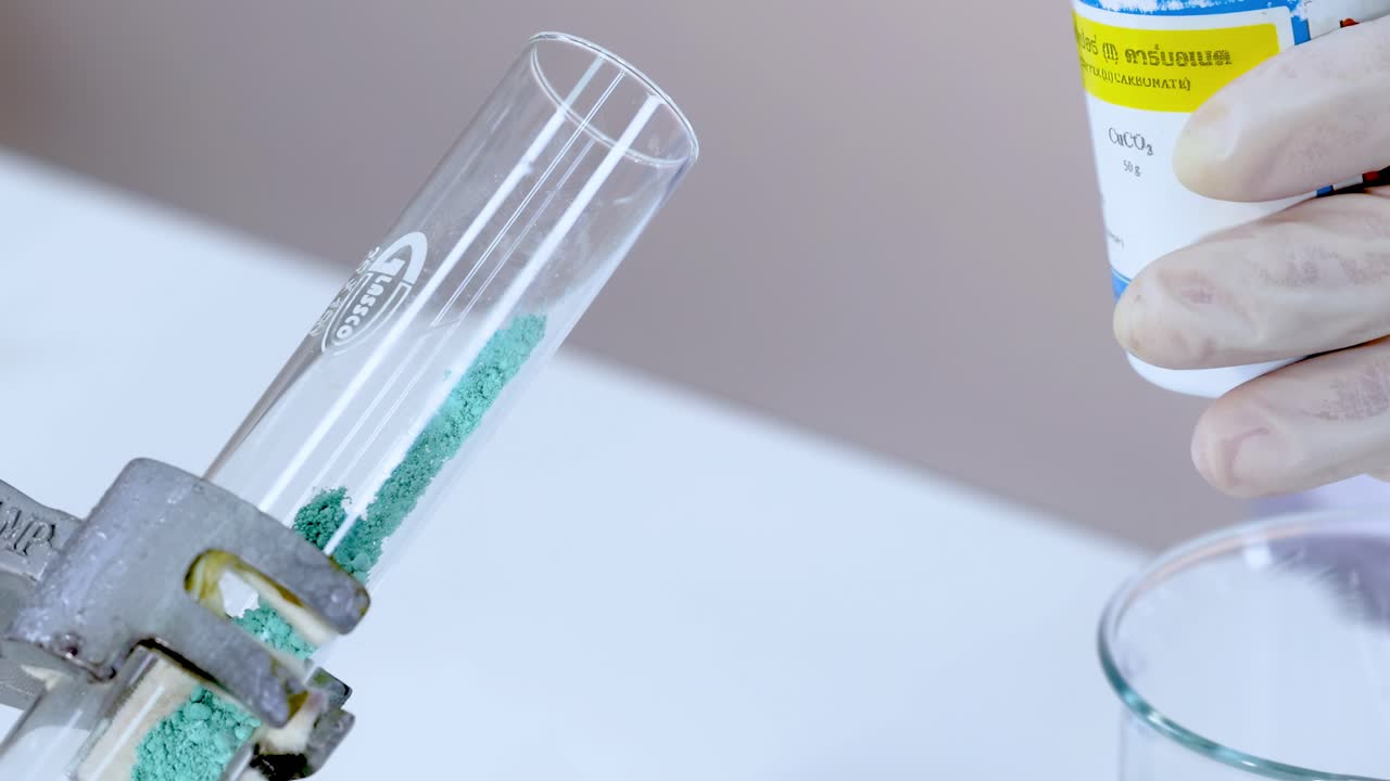 A close-up view of a green powder reacting in a test tube with a liquid.