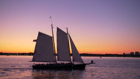 hudson-river-shot,-from-a-boat,-showing-sailing-ship,-at-dusk,-teal-and-orange-sky