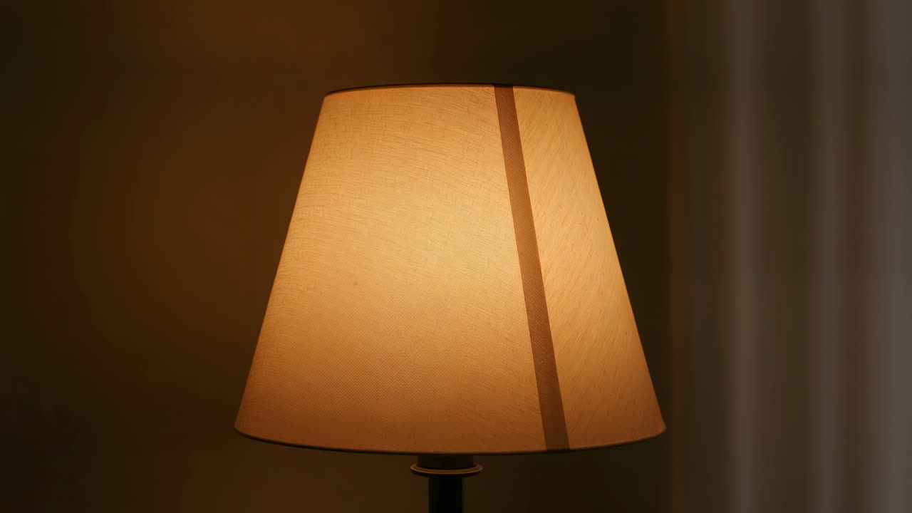 Lampada da tavolo appena accesa, posizionata al centro, che emette un bagliore ambrato con un effetto di luce a strisce per l'interior design.