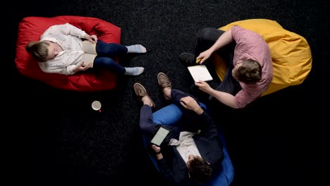 three workers are sitting on poufs and relaxing, conversation, office concept, communication concept