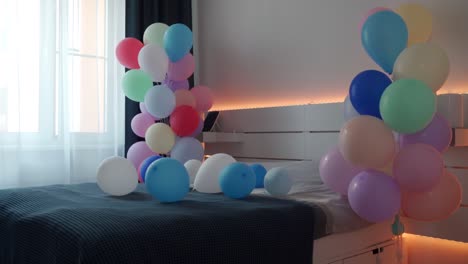 valentines day, romantic date and holidays concept - bed decorated with colorful balloons in bedroom.