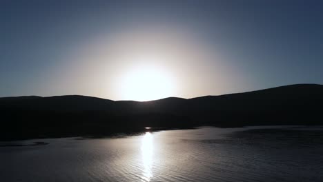 Reisen-über-Wasser-Bei-Sonnenaufgang-Mit-Bergen-In-Der-Silhouette