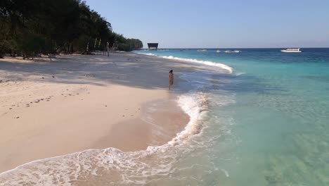 young happy woman running along the sea on tropical island having fun, turning around at shore