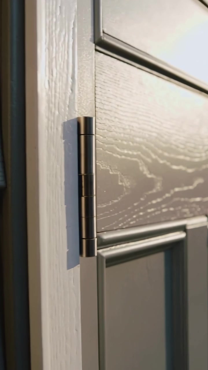 Video verticale: Telecamera in panoramica che rivela una porta d'ingresso con stipite e cerniera scura, rivestimento che mostra le venature.