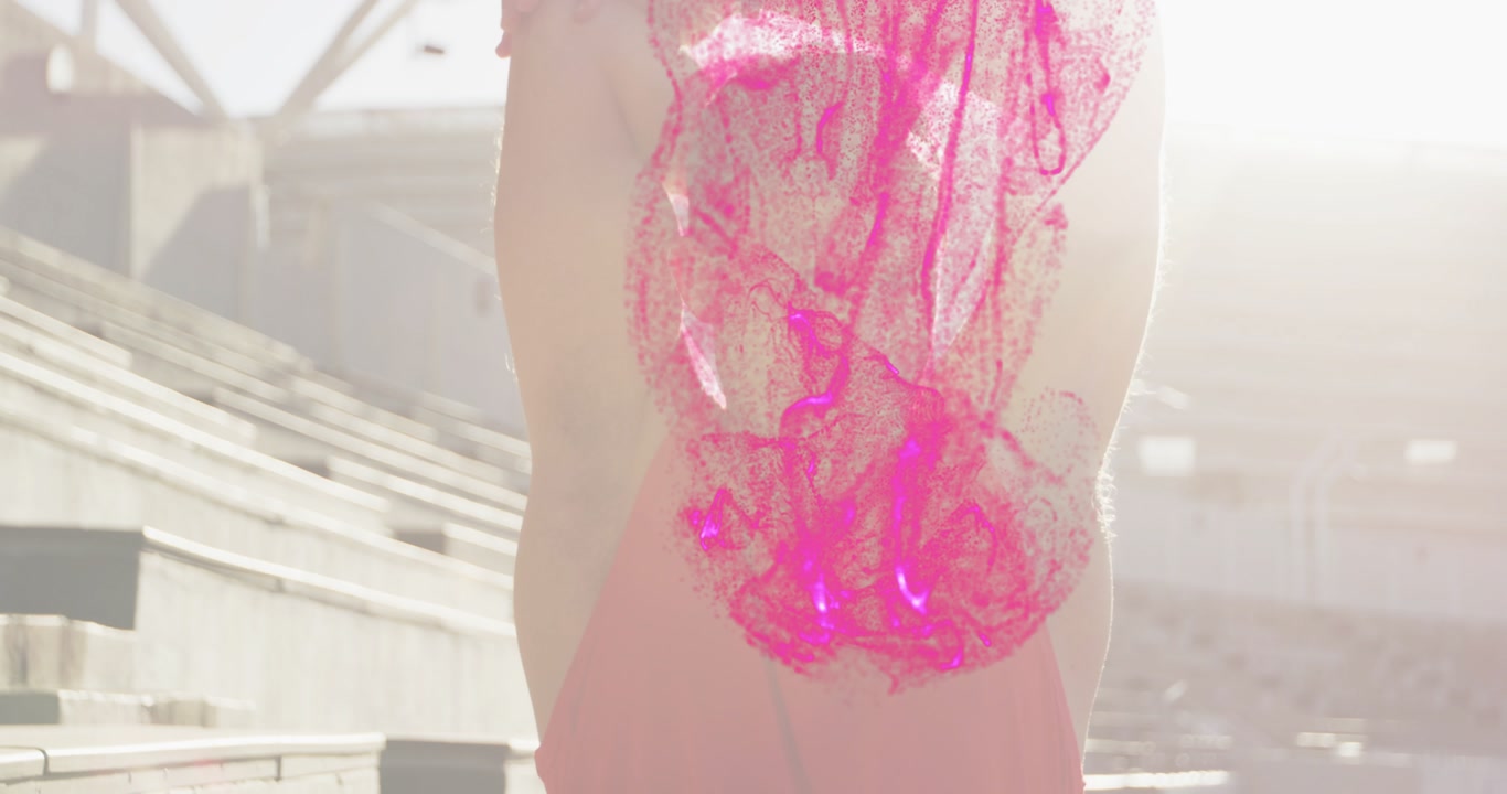 Man raising arms starting swirling pink particles down torso on sunlit stands for sports warm-up